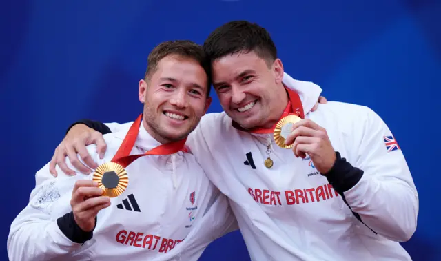 Alfie Hewett and Gordon Reid smile and hold up their Paralympic gold medals, while having their arms round each other's shoulders, following victory in the men's doubles