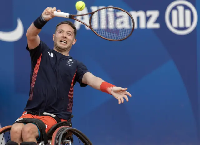 Hewett angles the racquet above his head to get the ball back