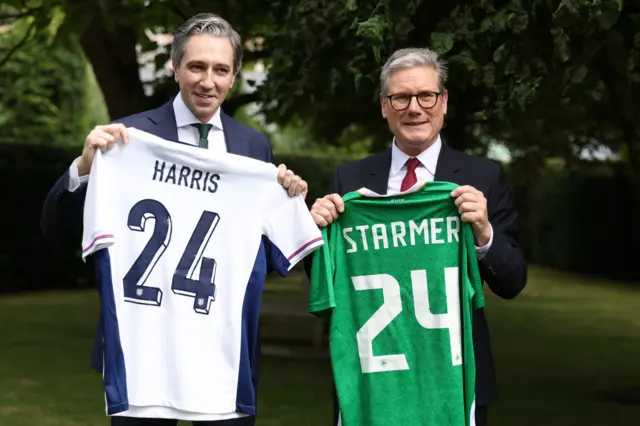 Taoiseach Simon Harris (left) and Prime Minister Sir Keir Starmer, hold up their respective teams shirts,