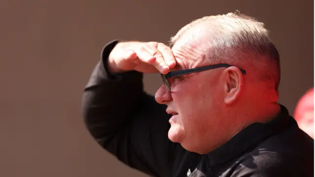 Steve Evans shielding his eyes from the sun