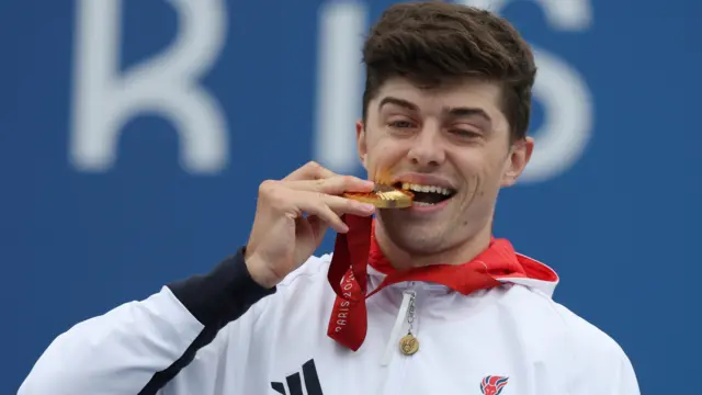 Fin Graham pretends to bite his gold medal