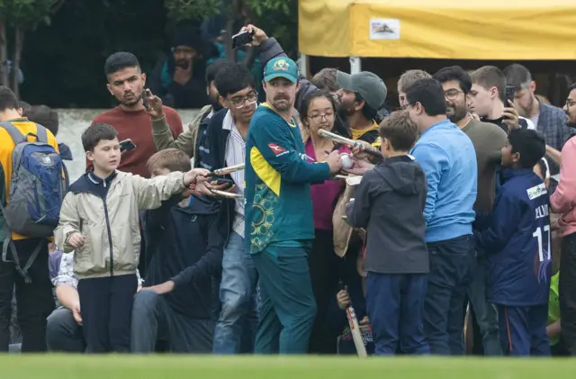 Travis Head signs autographs while fielding for Australia