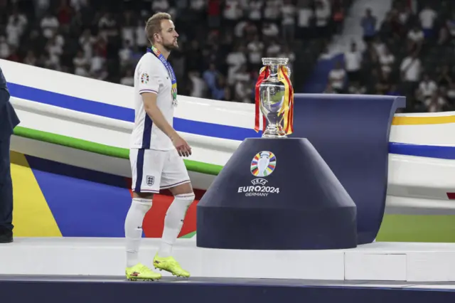 Harry Kane walks past the Euro 2024 trophy