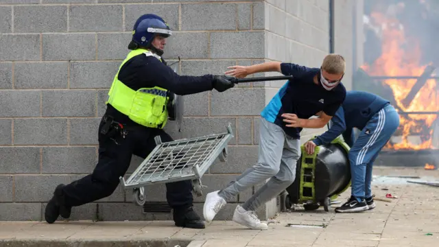 A police officer clashes with a protestor outside a hotel in Rotherham