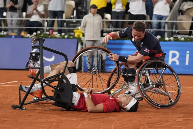 Alfie Hewett picks up a wheel from Tokito Oda's chair while the Japanese player lies on his back on the court after the Paralympic wheelchair tennis men's singles final