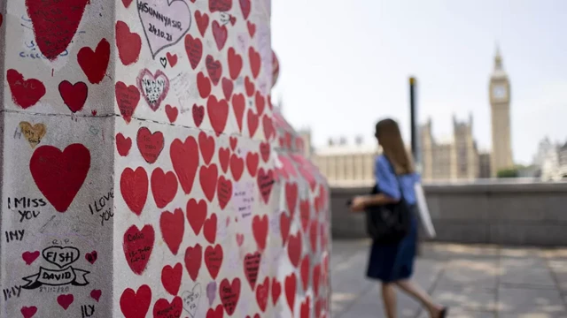 a woman walks past the Covid memorial wall in London