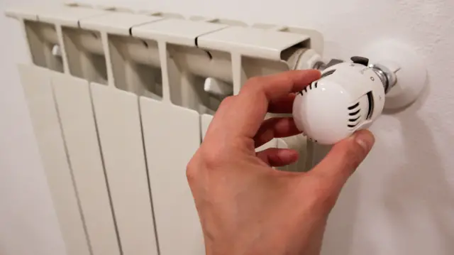 A hand adjusting the settings on a radiator