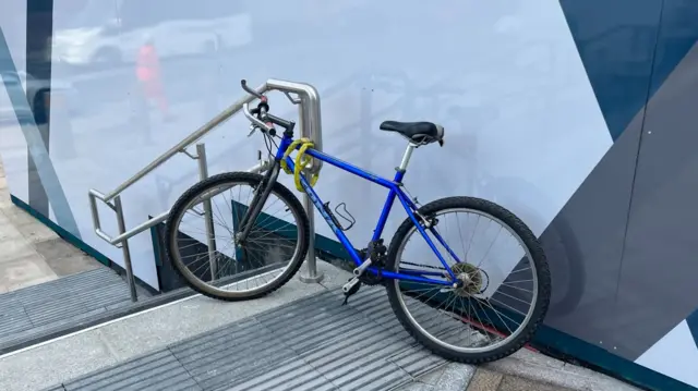 A bike chained to a rail outside the hub