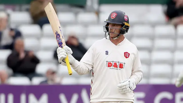 Tom Westley of Essex raises his bat to celebrate reaching his fifty