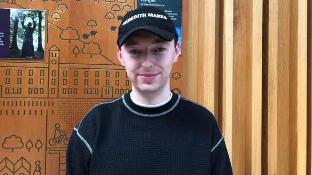 A man wearing a black cap and black jumper