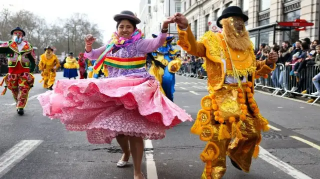 People dance in the middle of the street in traditional outfits.