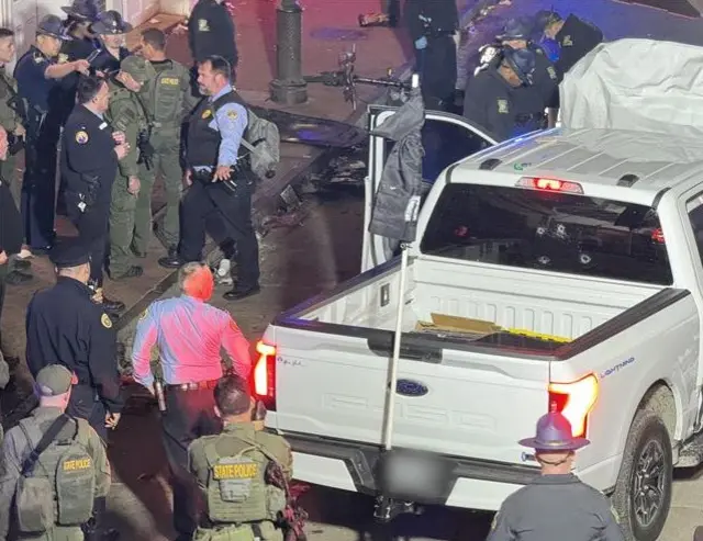 Ford F150 lightning truck, with police officers surrounding it and a heavily damaged bonnet pointing upwards. The driver's door is open.