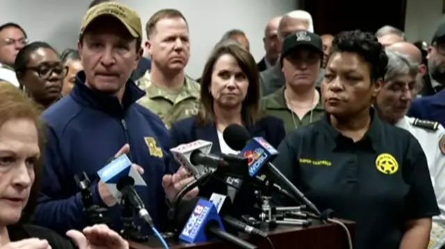 Louisiana Governor Jeff Landry speaking at a news conference in front of a lectern, with mayor LaToya Cantrell on his left