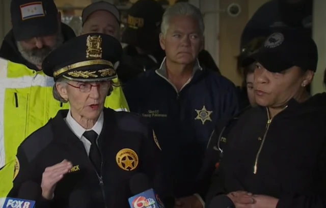 Kirkpatrick on the left in a police uniform speaking as the mayor stands next to her
