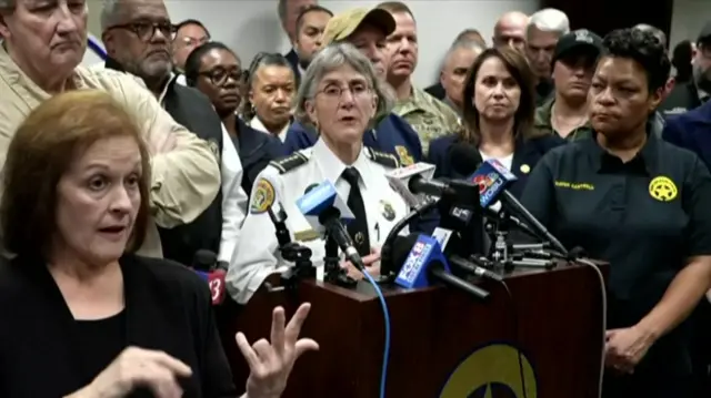 The superintendent of police Anne Kirkpatrick speaking at a news conference, surrounded by officials