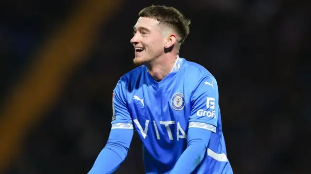 Stockport's Louie Barry smiles with his arms out wide as he asks to be played the ball