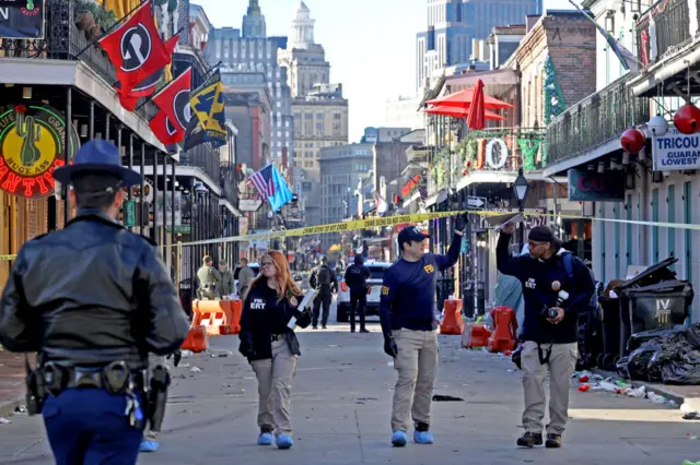 Three members of FBI lift up a yellow police cordon on a street in New Orleans