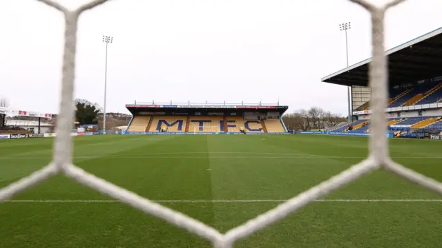 View of Mansfield Town's One Call Stadium from through the net behind a goal