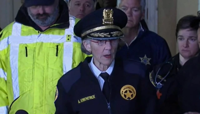Anne Kirkpatrick in her police uniform speaking. People stand behind her