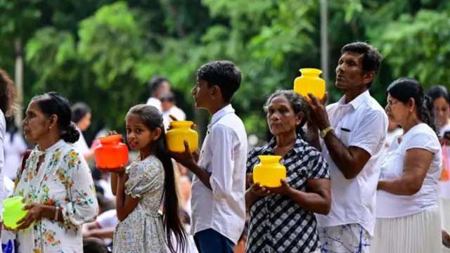 Devotees hold water pots before offering prayers during New Year's Day at Kelaniya Buddhist temple in Kelaniya