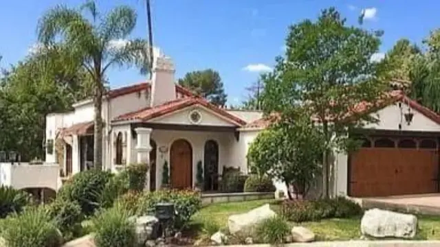 Image of a big house with some trees and other greenery around it