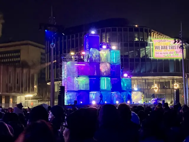 People in large illuminated cubes perform on stage