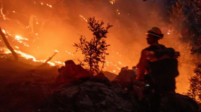 A firefighter battles the fire in the Angeles National Forest near Mt. Wilson as the wildfires burn in the Los Angeles area