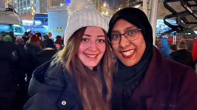 Two women in big coats smile for the camera