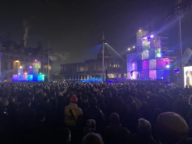 Large crowds look to an illuminated stage