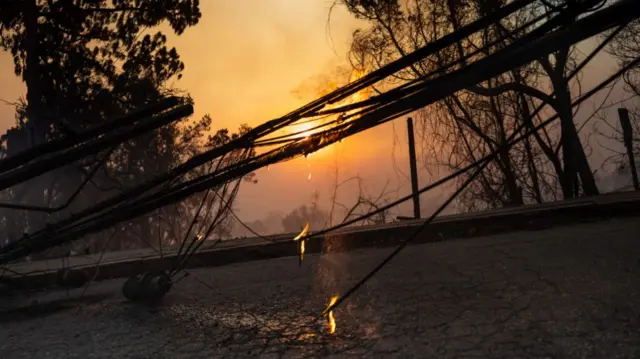 Downed power lines are aflame, destroyed in the Palisades Fire, on January 8, 2025 in the Pacific Palisades community