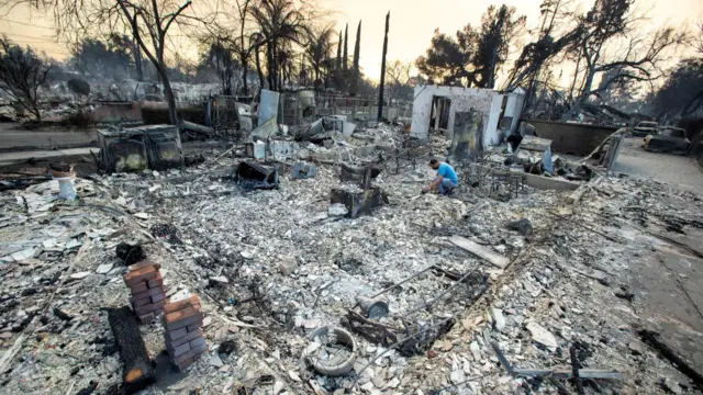 Man looks at remains of destroyed home in California