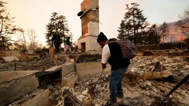 Jess Willard looks for his belongings amidst the debris from his home burnt down by the Eaton Fire