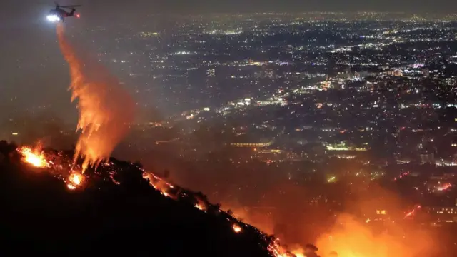 Aircraft dousing hill fire with water