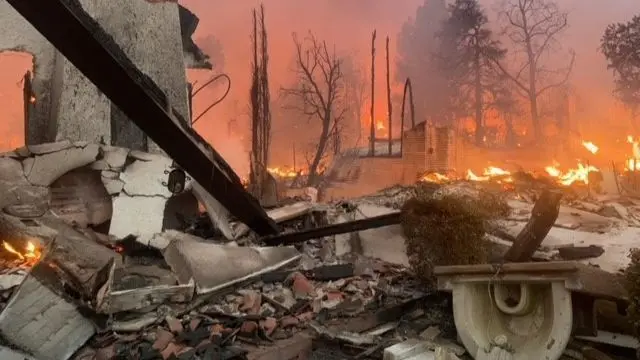 Remains of a burned down home, with active flames still visible