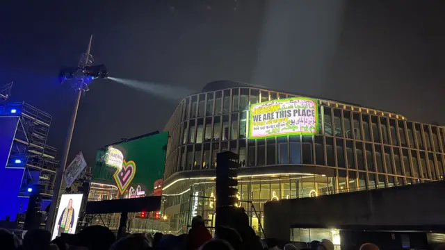 Light shone onto a building highlight a message of 'We are this place'