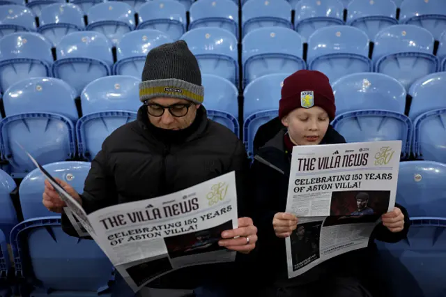 Aston Villa fans are seen reading 'The Villa News' to commemorate the club's 150th anniversary