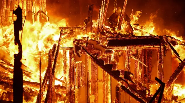 The burning inside of a bulding, showing flames going up stairs