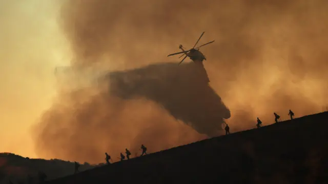 A helicopter drops water on the Kenneth wildfire in the Woodland Hills