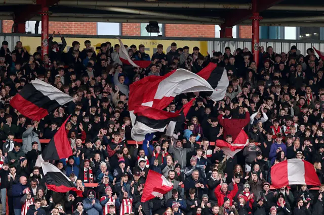 Fans of Exeter City wave flags and reacts