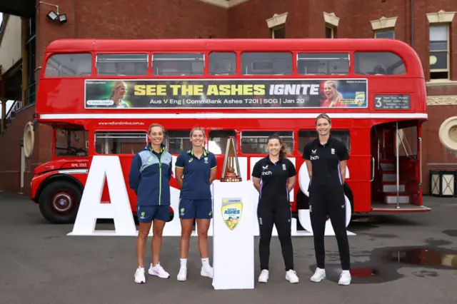 Ashleigh Gardner and Phoebe Litchfield of Australia and Tammy Beaumont and Lauren Bell of England pose during with Women's Ashes trophy behind a routemaster bus at the at the Sydney Cricket Ground