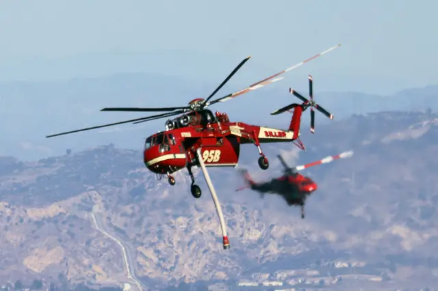 CalFire helicopters carry water as the Palisades Fire grows near Encino Hills, California, on January 11, 2025