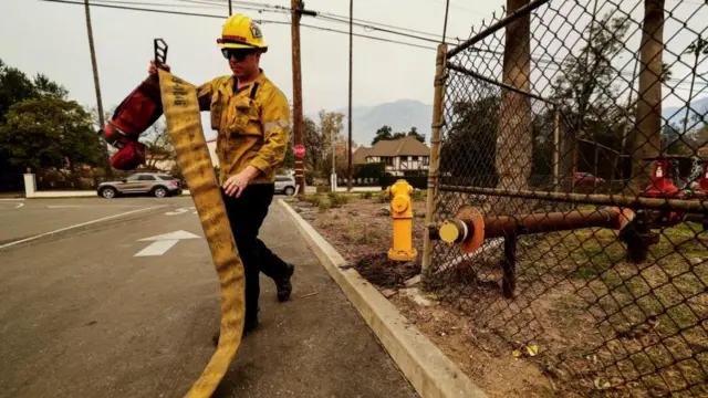 Firefighter holding an empty hose and walking away from a fire hydrant