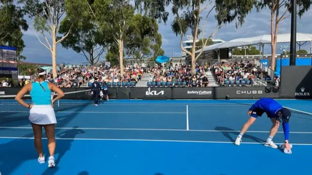 Ball boy dabs court with towel