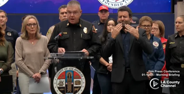 Anthony C. Marrone in black shirt standing at podium at press conference