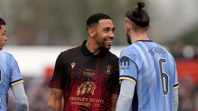 Tamworth's Jordan Cullinane-Liburd (centre) speaks with Tottenham Hotspur's Radu Dragusin