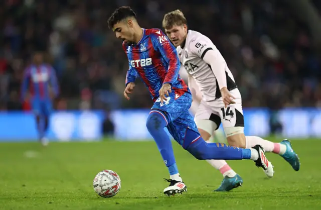 Chadi Riad of Crystal Palace runs with the ball whilst under pressure from Will Collar