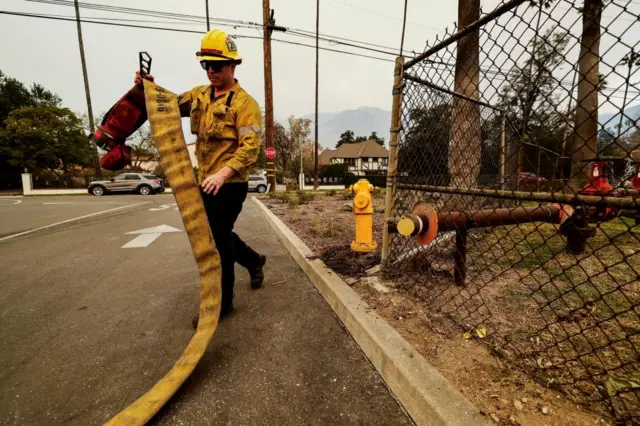 Firefighter holding an empty hose and walking away from a fire hydrant