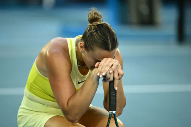 Sabalenka crouches on the ground