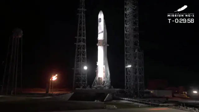 The Blue Origin rocket lit up against a black sky at Cape Canaveral