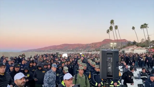 Officials in police and military garb stand and face forward